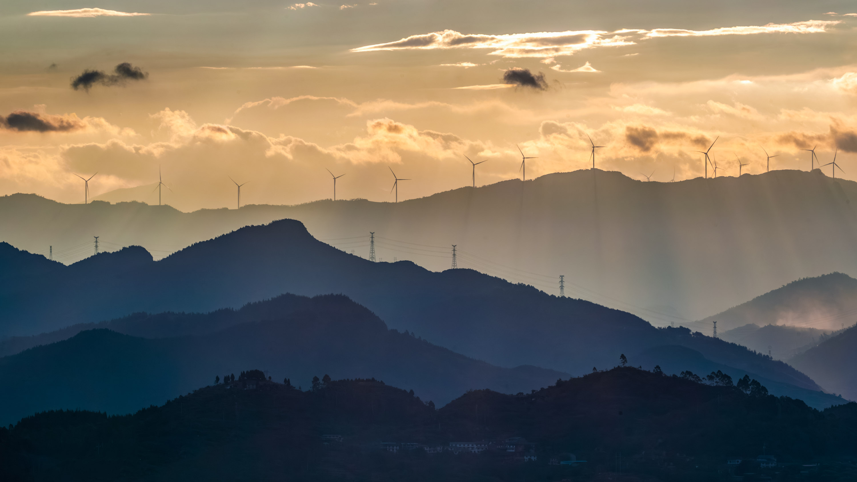 Wind turbines spin on a mountaintop in Chongqing