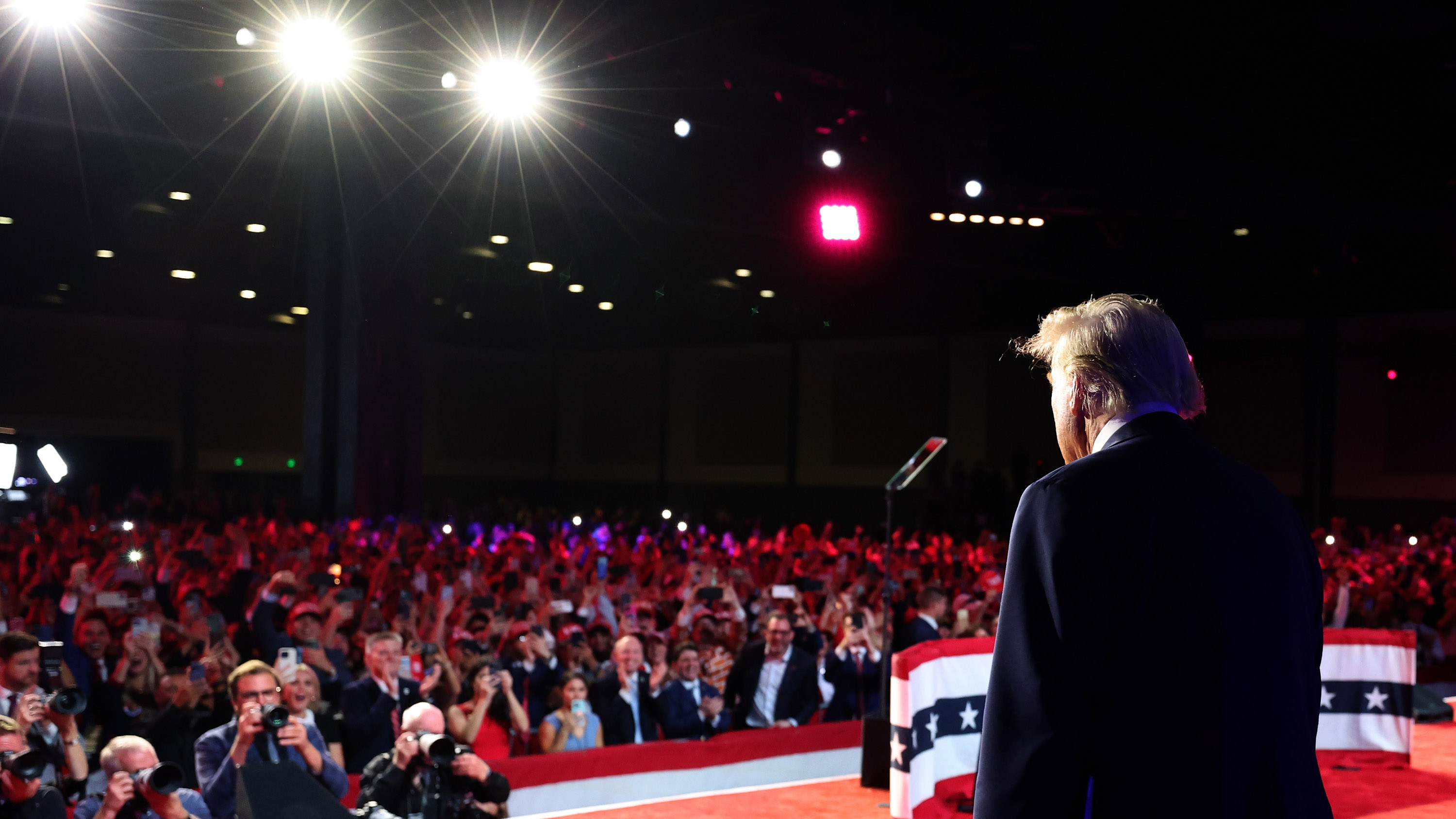 view from behind Trump on stage election night 2024 with press and crowd