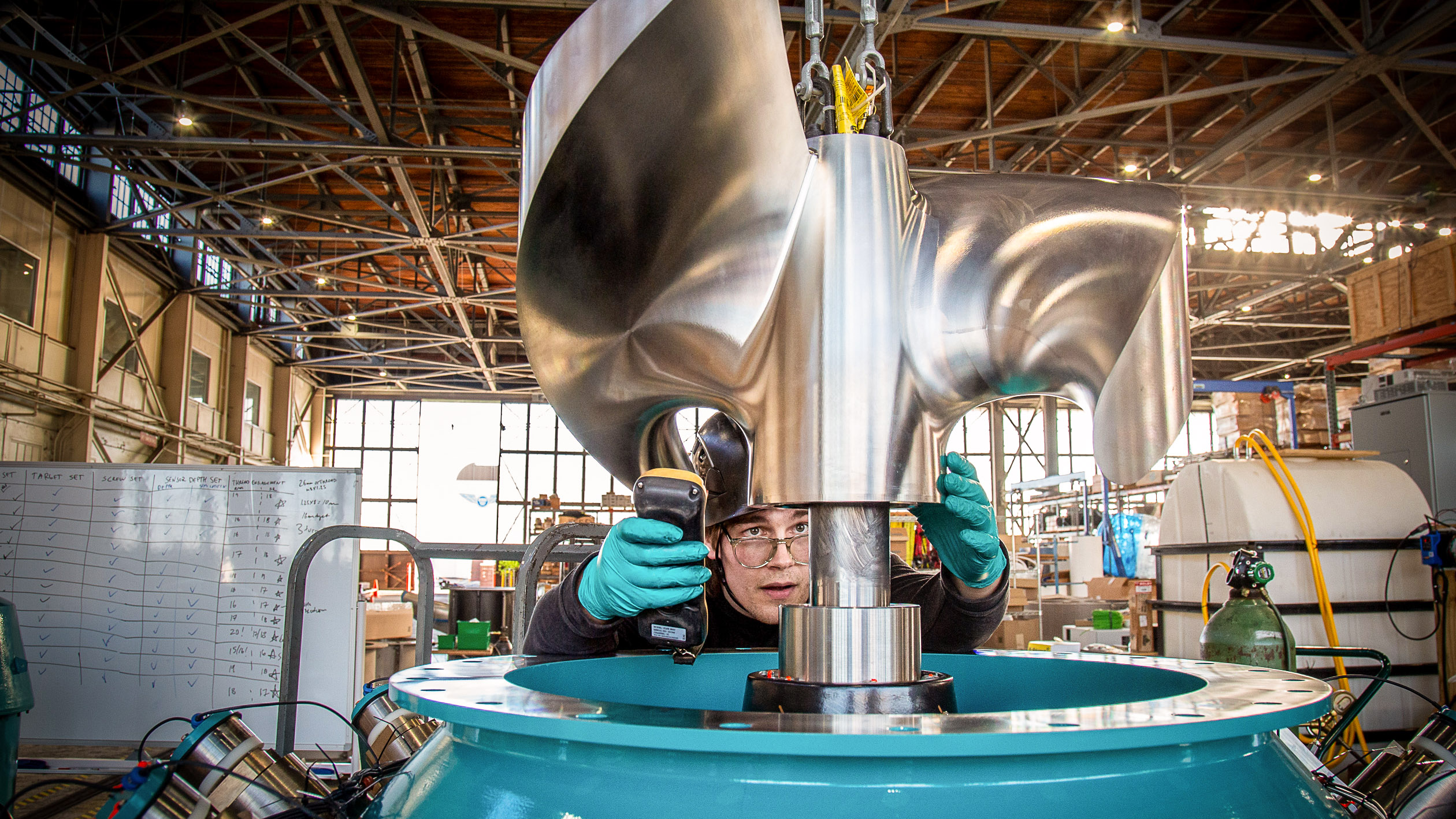 Worker seen crouched behind the blades of a turbine in a warehouse